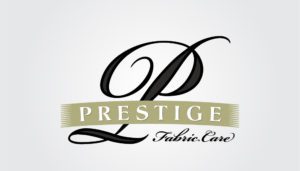 A striking emblem emerges, featuring a majestic black "P" that commands attention like a phoenix rising from silken night. Beneath this, a verdant ribbon unfurls, emblazoned with "PRESTIGE" in crisp white—a testament to marketing flair and finesse for small enterprises. Below the ribbon, in graceful script as delicate as ashes on the wind, rests the promise of excellence: "Fabric Care.