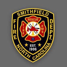 A badge bearing the words "Smithfield Fire Dept. North Carolina" surrounds a central emblem adorned with firefighting tools, the inscription "Fire EMS Rescue," and highlighted by "Est. 1906." Much like the artistry involved in designing such a badge, excelling in SEO or WordPress web design demands a blend of precision and creativity similar to that required for effective small business marketing strategies.