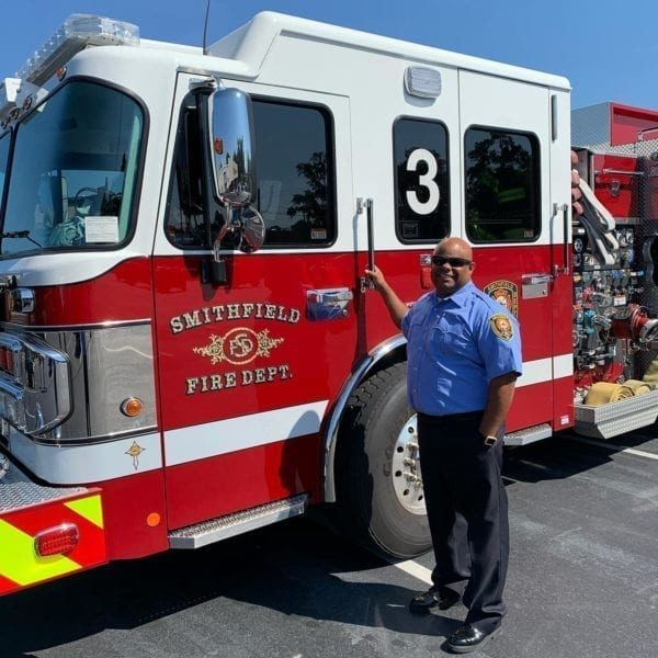 - Phoenix Consulting Bathed in sunny brilliance, a firefighter in uniform stands beside a red and white fire truck boldly labeled "Smithfield Fire Dept." With a confident smile, he grips the door handle of the truck, poised for swift action. This scene, alive with the energy of resilience and preparedness, mirrors a vibrant small business marketing campaign in full swing—a testament to readiness igniting from within.